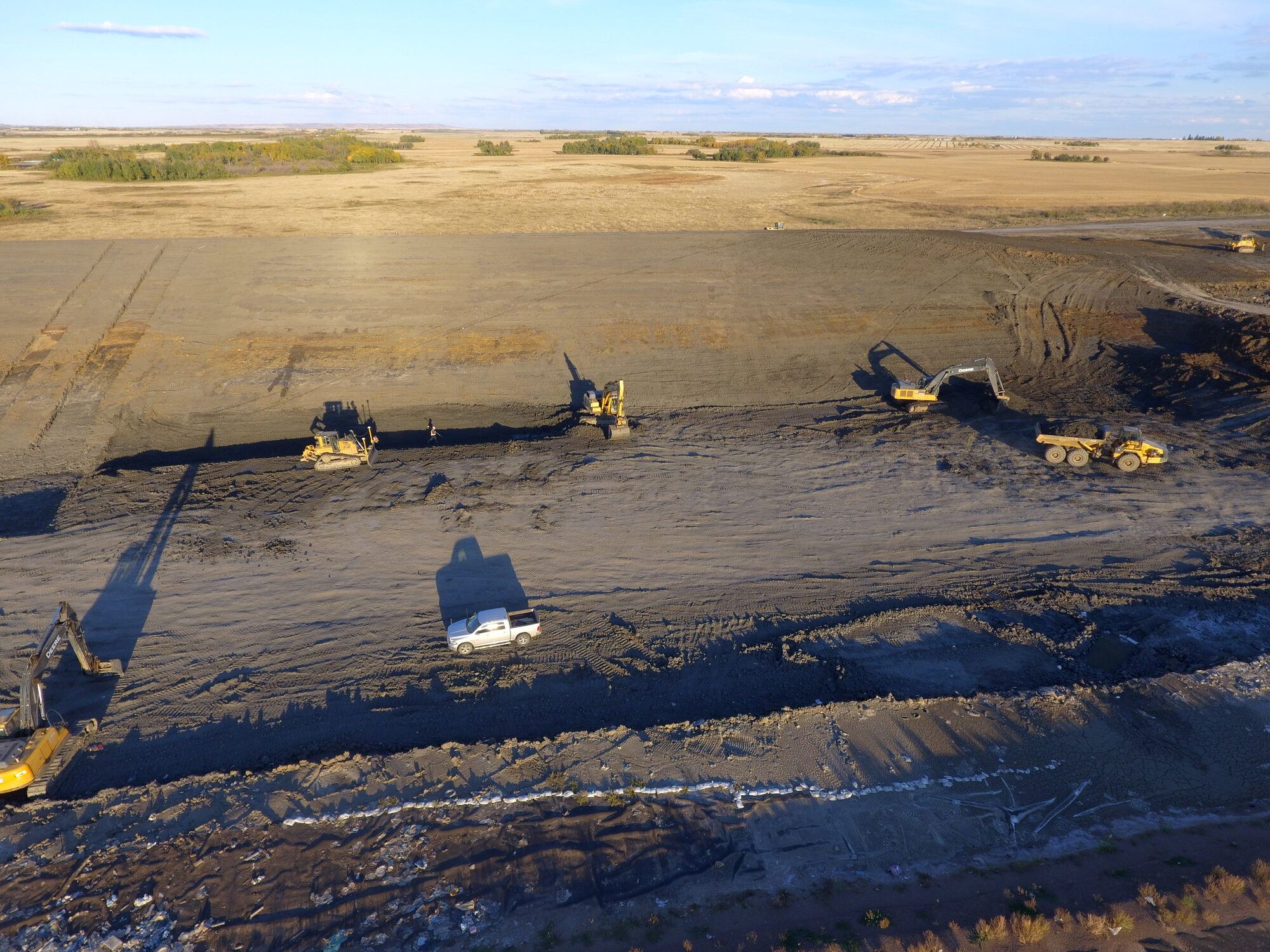 Aerial view of dozers and excavators building a lined landfill cell